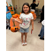 A little girl showing off her decorated pumpkin.