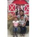 A woman, a girl, and a boy in front of a farm backdrop.