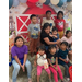 Kids sitting on a hay bale in front of a farm backdrop.