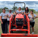 Women standing around a tractor.