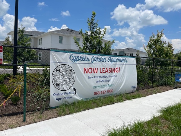 View of fence with a sign for Cypress Gardens Apartments.
